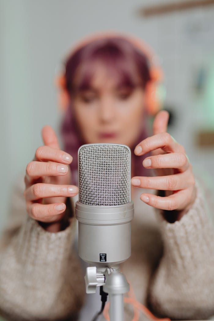gallery-5 Close-up of a woman recording ASMR with a microphone indoors.
